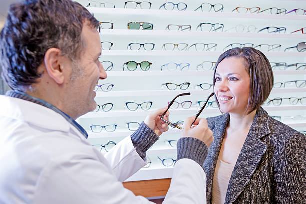 istock optician trying on glasses to a customer 530771301