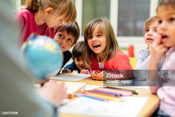 Preschool Teacher And Children Using Globe Stock Photo - Download Image Now - Child, Preschool, Education
