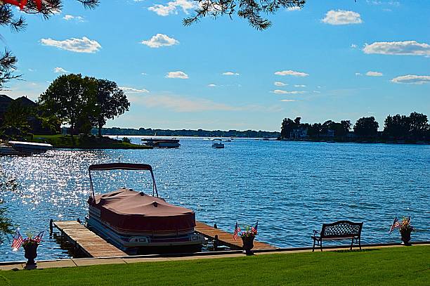 Pontoon boat by the lake Pontoon boat docked by a beautiful natural lake pontoon boat stock pictures, royalty-free photos & images