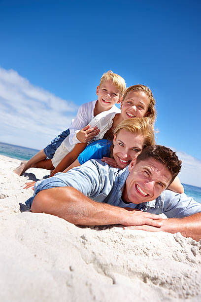 Beach pile-up! Portrait of a young family of four lying on the beach pileup stock pictures, royalty-free photos & images