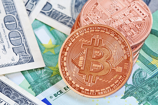 Prague, Czech Republic , October 25, 2014: Photo of golden bitcoins (new virtual currency) with traditional dollars and euro as a background .Symbol of a new virtual currency .