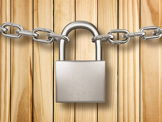 istock Locked padlock with silver chains isolated on wood background. 530794865