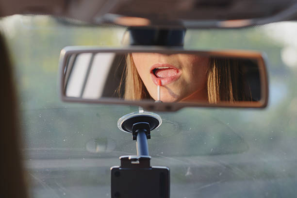 istock young woman using lipgloss in car 530803100