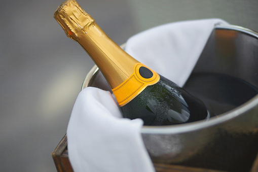Bottle of champagne in ice bucket in restaurant. Close up picture with bokeh.