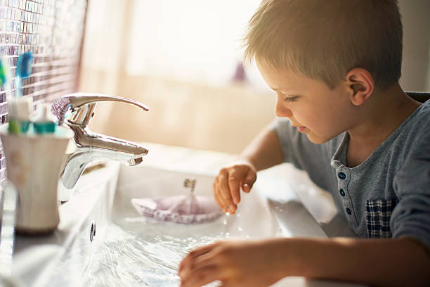 istock Little boy playing with paper boat in sink 530806290