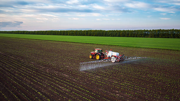 трактор земледелия на поле в весной напыления - cultivated land farm land plowed field стоковые фото и изображения