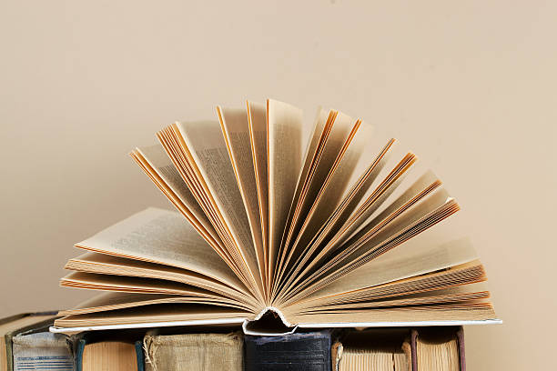istock Open book, stack of hardback books on wooden table. 530808822