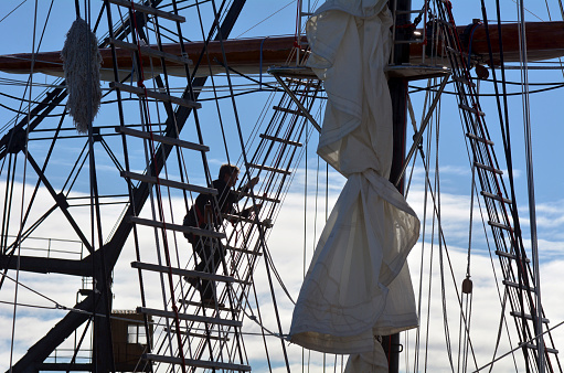 Auckland, New Zealand - June 01, 2014: Sailor climbs onto the mast of the Spirit of New Zealand. It's a tall ship with steel-hulled, three-masted barquentine that was built by the Spirit of Adventure Trust in 1986.
