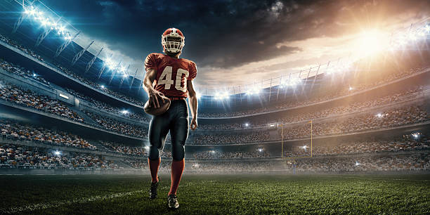 American football player Professional American football player standing on a sport stadium with spotlight. Player is wearing unbranded football cloths.  american football field photos stock pictures, royalty-free photos & images