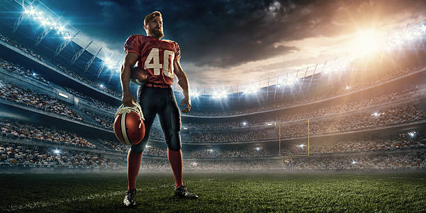 American football player Professional American football player standing on a sport stadium with spotlight. Player is wearing unbranded football cloths. Professional American football player standing on a sport stadium with spotlight. Player is wearing unbranded football cloths.  football helmet and ball stock pictures, royalty-free photos & images