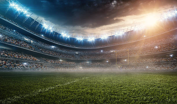 Dramatic american football stadium A wide angle panoramic image of a outdoor american football stadium full of spectators under evening sky. The image has depth of field with the focus on the foreground part of the pitch. The view from center of the field. floodlight photos stock pictures, royalty-free photos & images