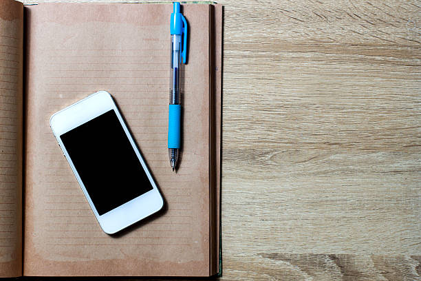 istock Open diary and smartphone on wooden background 530811689