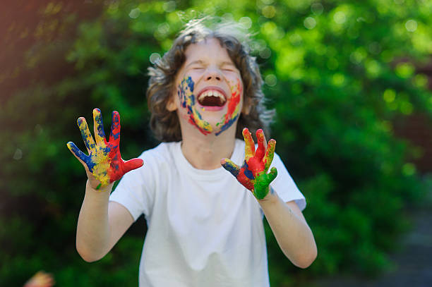 istock The boy laughs, his face and hands in the paint 530813544