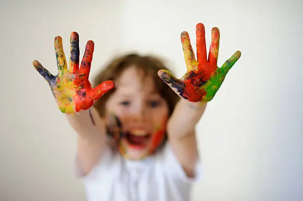 Photo of Child face and hands in the paint, he laughs