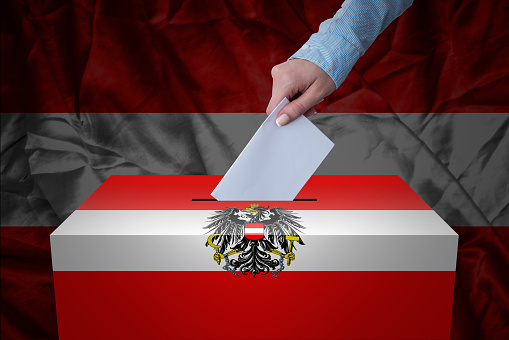 A hand casting a vote in a ballot box for an election in the Austria