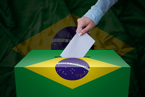 A hand casting a vote in a ballot box for an election in the Brasil