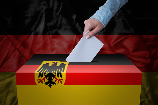 A hand casting a vote in a ballot box for an election in the Germany