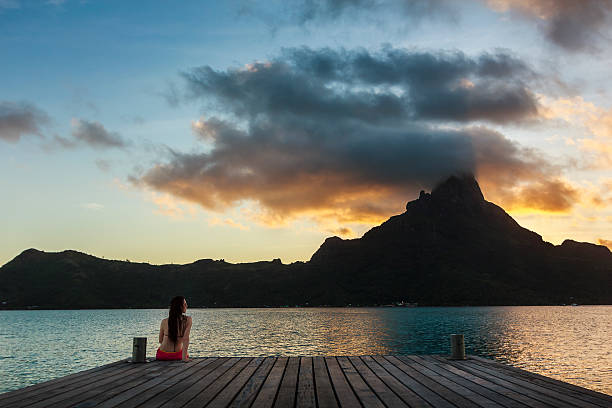 Girl Sitting on Pier in Bora Bora at Sunset