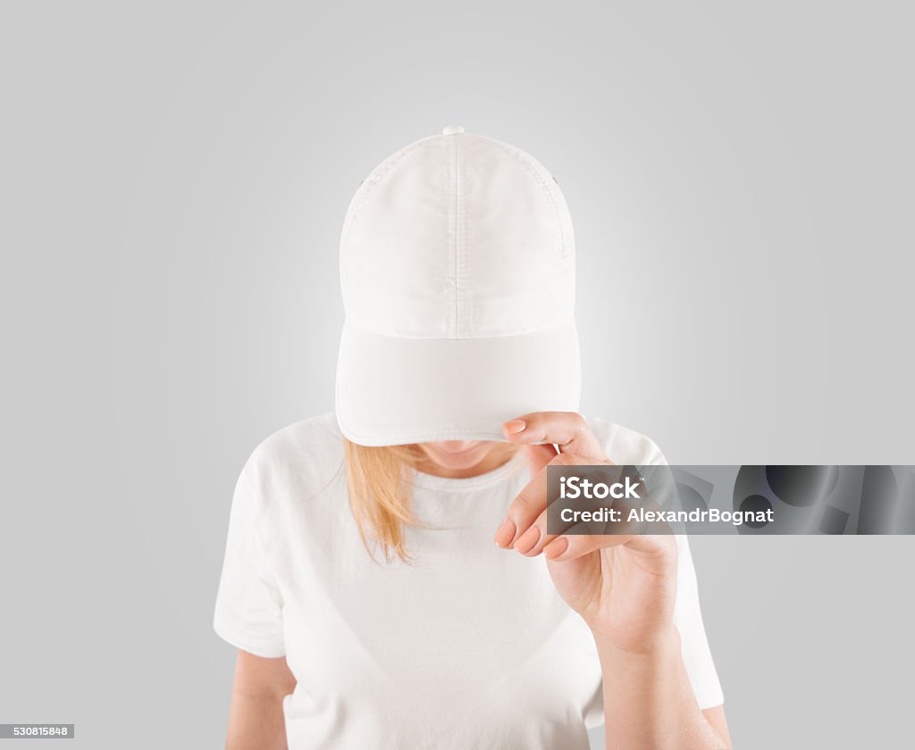 Blank white baseball cap mockup template, wear on women head Blank white baseball cap mockup template, wear on women head, isolated, clipping path. Woman in clear hat and t shirt uniform mock up holding visor of caps. Cotton basebal cap design on delivery guy. White Color Stock Photo