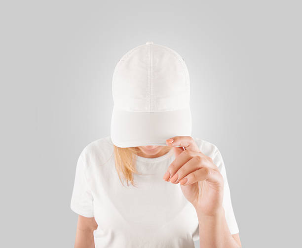 Blank white baseball cap mockup template, wear on women head Blank white baseball cap mockup template, wear on women head, isolated, clipping path. Woman in clear hat and t shirt uniform mock up holding visor of caps. Cotton basebal cap design on delivery guy. baseball cap stock pictures, royalty-free photos & images