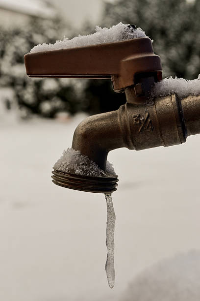 Frozen water coming from tap, droplet freezes A small amount of water freezes into an icicle as it comes out of a tap, snow covers the ground in this picture. The tap has a snow covered red handle. This picture could be used to symbolize the problems with plumbing in the winter months. frozen water stock pictures, royalty-free photos & images