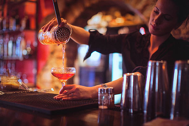 jeune femme barman servant des cocktails dans un bar à cocktails - cocktail alcohol red martini glass photos et images de collection