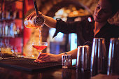 Young female bartender pouring cocktails in a cocktail bar