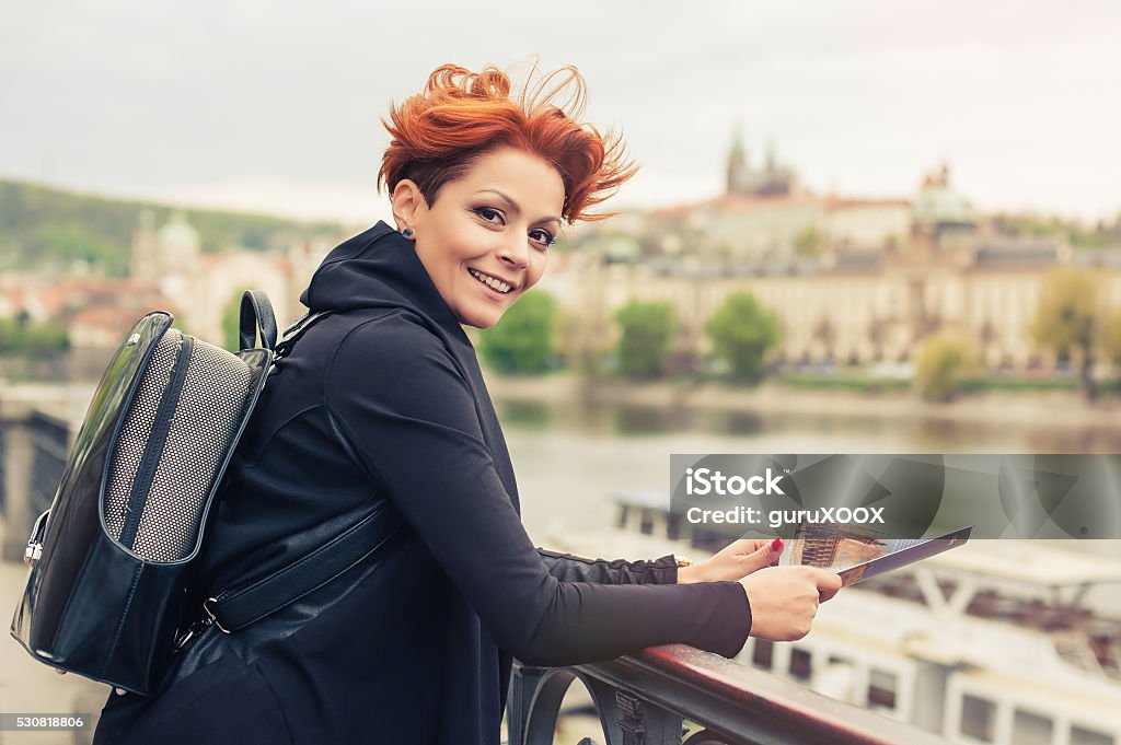 Female tourist looking at city guide Female tourist standing near river and looking at city guide Adult Stock Photo