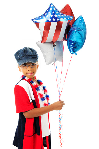 A young elementary girl looking at the viewer as she holds a bunch of red, white and blue balloons.  On a white background.