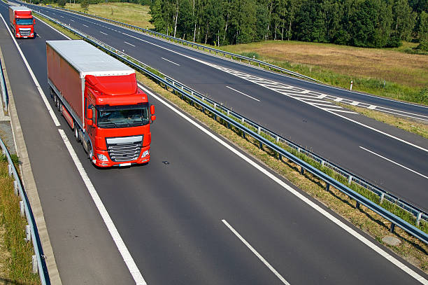 istock Two red trucks riding on an empty asphalt highway 530820290