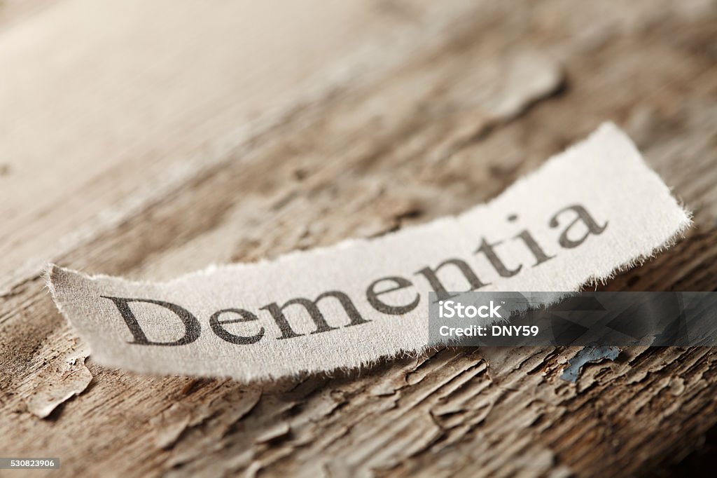 Dementia Concept The word 'Dementia" on a torn piece of paper that rests on an old weathered piece of wood.  The old paint is flaking off of the wood surface to help convey the feeling of age. Alzheimer's Disease Stock Photo