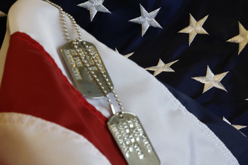 A pair of dog tags laying over the US flag.