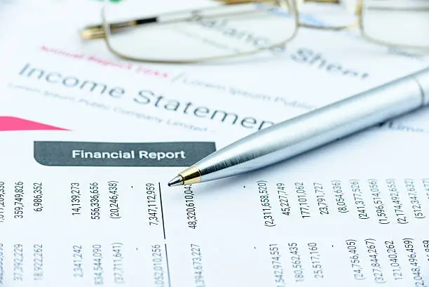 Photo of Blue ballpoint pen on a quarterly corporate financial report.