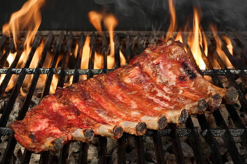 BBQ Roasted Pork Baby Back Or Spareribs On The Hot Charcoal Grill With Flames, Closeup