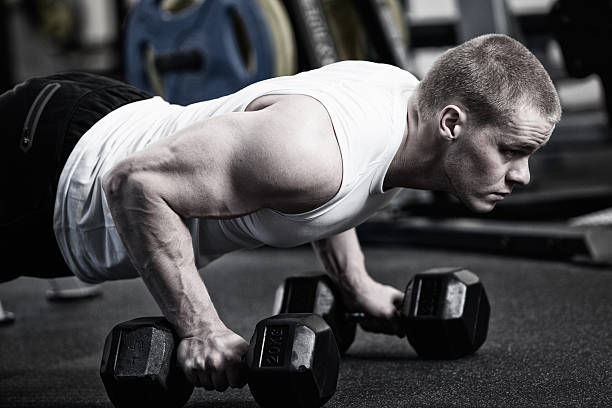 istock Photo Man doing push up holding dumbbell at the gym 530830682
