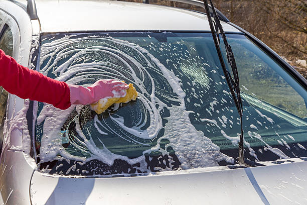 istock Hand in protective glove washing a cars window with sponge. 530830786