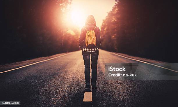 Traveler With Backpack Walking Forward Alone At Sunset Stock Photo - Download Image Now