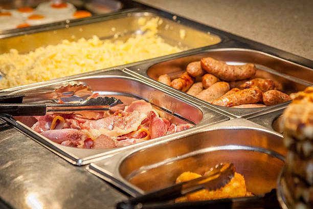 Hot breakfast counter Hot counter containing warm breakfast items such as scrambled or fried eggs, bacon, sausages, grilled tomatoes buffet stock pictures, royalty-free photos & images