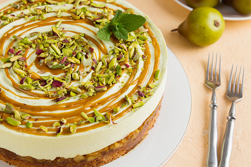Mousse cake with caramelized pear decorated with caramel and pistachio. Shallow focus