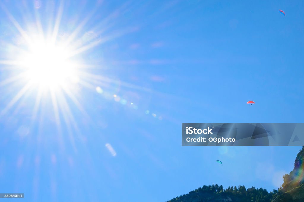 Paragliding with bright sun Paragliders near a mountain with the  sun creating lens flare. In the Lauterbrunnen Valley, Switzerland 2015 Stock Photo