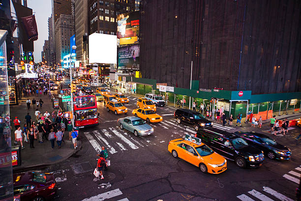 Close up cityscape of busy street of Manhattan at night time with tall office buildings in New York