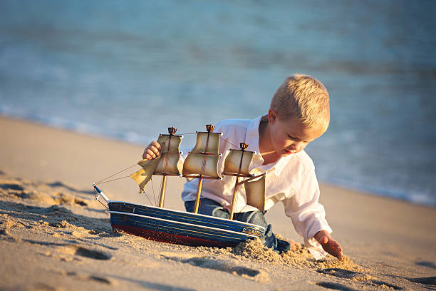 istock Little Boy with Big Dreams Playing with Pirate Ship on Beach 530843345