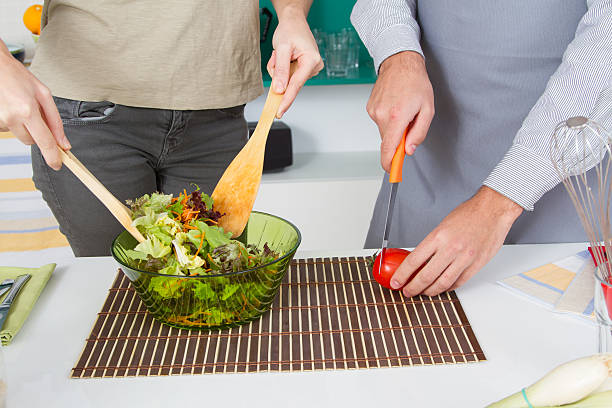 istock Close-up couple hands preparing salad in a bowl 530853895