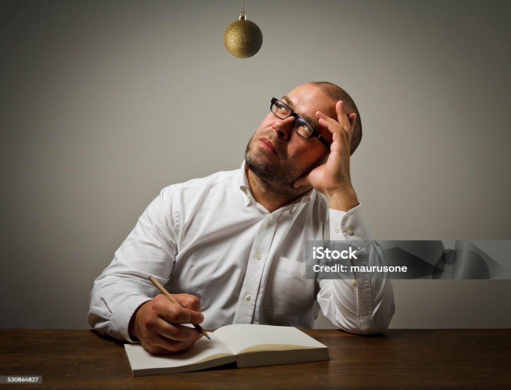 Man in white and Christmas toy. Man in white and Christmas ball which is above his head. Man in white is ready to write something. Christmas Stock Photo