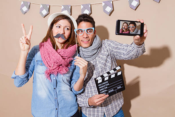 若いカップルの写真撮影装置のパーティで演出の顔 - telephone booth ストックフォトと画像