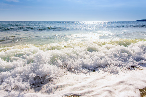 sand sea beach and blue sky after sunrise and splash of seawater with sea foam and waves