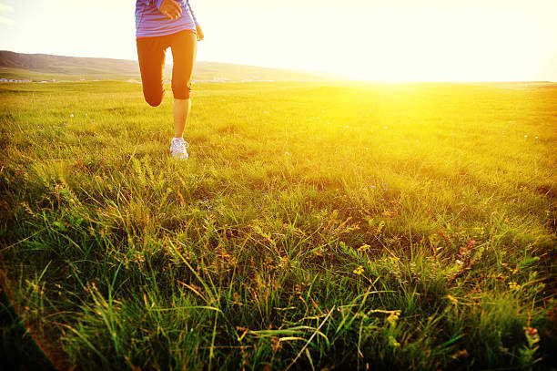 istock Runner athlete legs running on sunny grass field 530877583