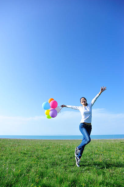 istock young asian woman running and jumping with colored balloons 530877657