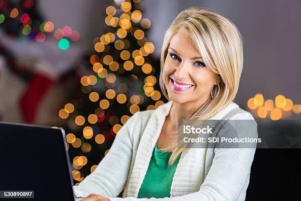 Beautiful Blonde Woman Using Laptop At Home During Christmastime Stock Photo - Download Image Now