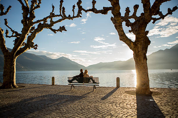 istock Young couple sitting back to back on bench at sunset 530901691